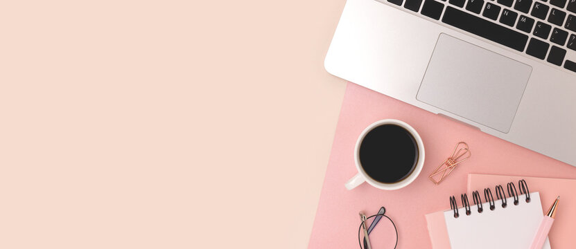 Banner with office supplies, laptop and cup of coffee on a beige and pink background. Business workspace with place for text.