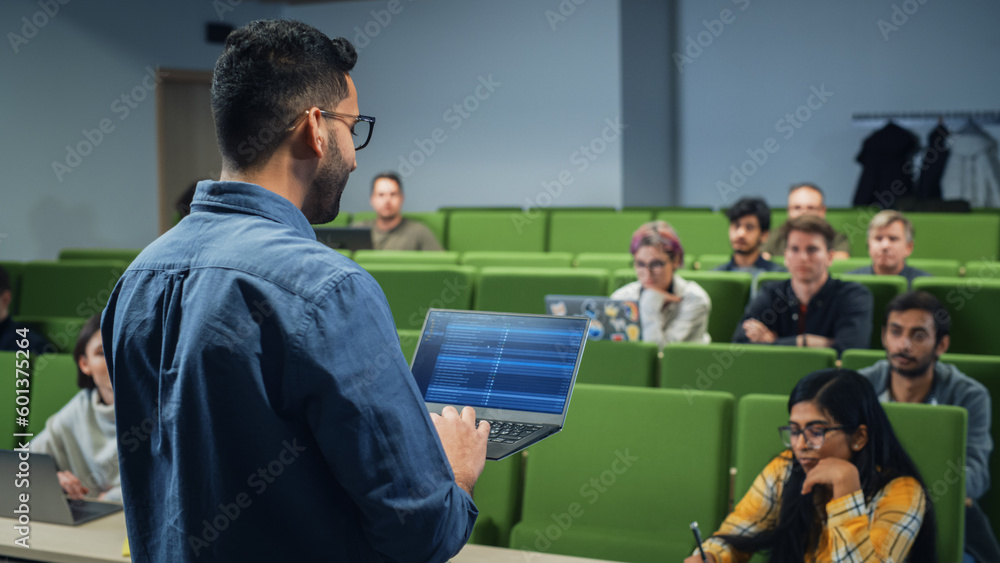 Fototapete University Professor Explaining the Importance of a College Degree to a Group of Diverse Students in a Modern Auditorium. Teacher Holding a Laptop Computer and Talking to Scholars. Camera Facing Class