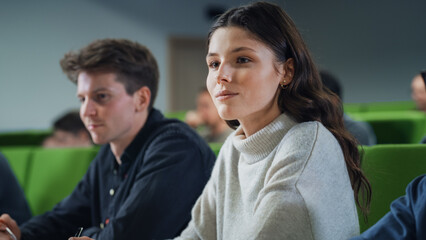 Talented Smart Female Student Studying in College with Diverse Multicultural Colleagues. Young Woman Focused on a Lecture, Writing Down a Summary in Her Notebook