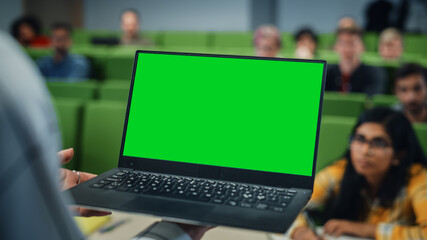 Close Up of an University Professor Using a Laptop Computer with a Green Screen Mock Up Display. Female Teacher Giving a Lecture to a Class of Talented Diverse Young Men and Women.