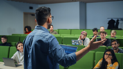 Male Teacher Giving a Lecture to a Diverse Multiethnic Group of Female and Male Students in Modern College Room. Curious and Thoughtful Scholars Studying and Listening to Lecturer. Camera Facing Class