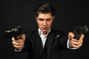 Young mafia member with a slicked back hair, in black suit, cigar behind the ear, hold and pointing...