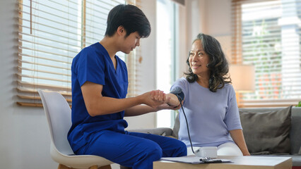 Male caregiver measuring blood pressure of a senior woman. Hypertension, medical and health care concept