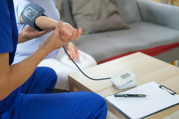 Home health care service concept. Healthcare worker measuring blood pressure senior woman during home visit.