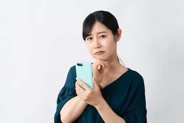スマートフォンを持ちながら悩む若い女性　ライフスタイルイメージ