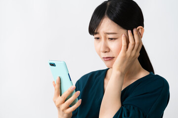スマートフォンを持ちながら頭を抱える若い女性