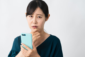 スマートフォンを持ちながらネガティブな表情をする若い女性