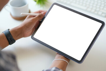 Close up view of man hand holding digital tablet over white working desk. Blank screen for