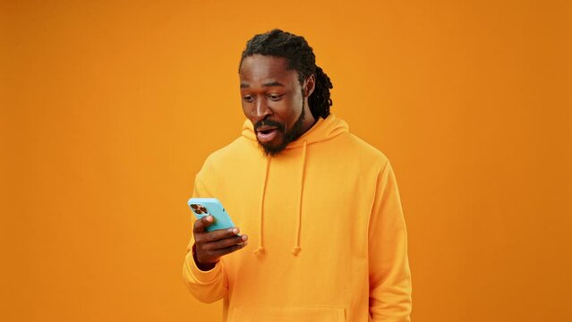 African man recieved good news via smartphone against yellow background