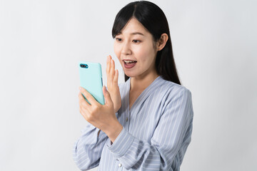 スマートフォンを持ちながら驚く若い女性