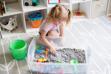 little girl playing with kinetic sand. Sensory box for kids