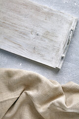 A white wooden tray and a coarse linen napkin on a gray concrete table