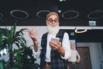 Thoughtful senior man chatting on smartphone in office