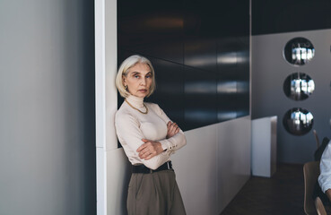 Fototapeta na wymiar Confident mature woman standing in office building and looking at camera