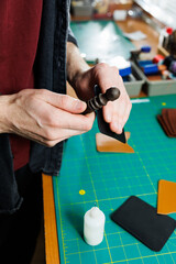 The hands of the master sew handmade leather products. Men's hands connect the parts, creating quality leather accessories. Working process in a leather workshop