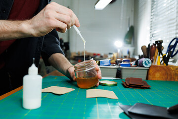 The hands of the master sew handmade leather products. Men's hands connect the parts, creating quality leather accessories. Working process in a leather workshop