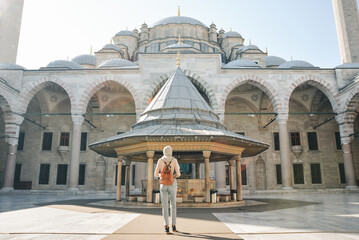 A young female traveler with a backpack on her back walks towards the Fatih Mosque in Istanbul