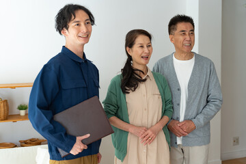作業着を着た日本人男性とシニアの日本人夫婦