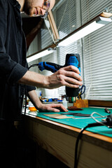 The hands of the master sew handmade leather products. Men's hands connect the parts, creating quality leather accessories. Working process in a leather workshop