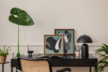 Modern composition of workplace interior with black desk, rattan chair, colorful sculpture, vase with leaves, rack, books, wall with stucco and personal accessories. Home decor. Template.