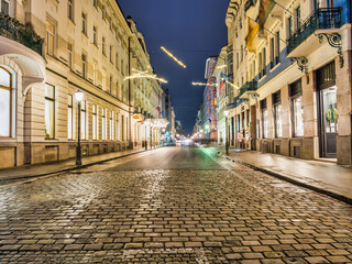 Fototapeta na wymiar Cobblestone Miklosiceva Street lit up with Christmas lights at night in Ljubljana, Slovenia