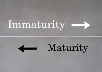 Wall with text inscription direction to opposite way MATURITY and IMMATURITY, maturity means to...