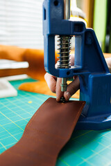 Close-up of the master's hands sewing handmade leather products. A men's tanner connects the parts,...