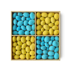 Yellow and blue candied dragee in square wooden tray isolated on white background top view 