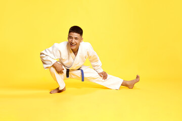 Portrait with young man, taekwondo, karate athlete wearing white kimono preparing for a duel over...