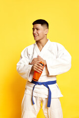 Portrait with young man, taekwondo, karate athlete wearing white kimono relaxing after fight over...