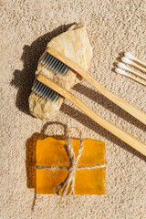 Creative layout made of two toothbrushes, natural soap and cootton buds on sunlit background with towels. Morning routine concept. Top view. Flat lay