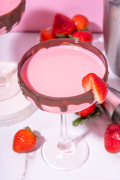 Sweet chocolate strawberry cocktail, cute pink strawberry martini or daiquiri creamy drink, with fresh strawberry garnish and choco drizzles, on high-colored pink background