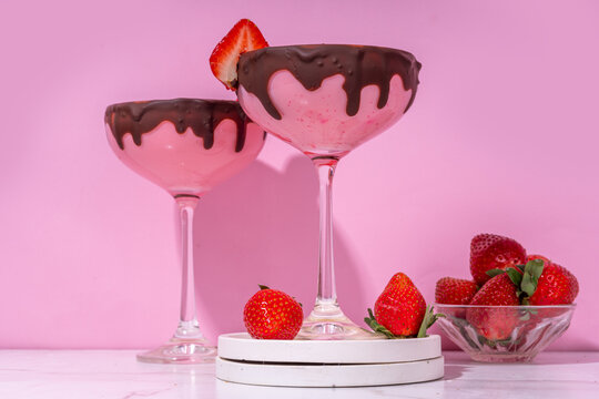 Sweet chocolate strawberry cocktail, cute pink strawberry martini or daiquiri creamy drink, with fresh strawberry garnish and choco drizzles, on high-colored pink background