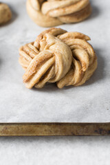 Swedish cinnamon buns dough on a parchment lined baking pan, unbaked cinnamon twists, process of making Kanelbullar