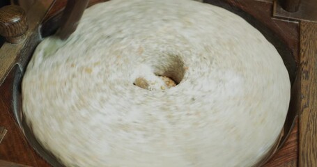 The baker grinds grain into flour. Antique hand mill in operation with an authentic 200 year old millstone