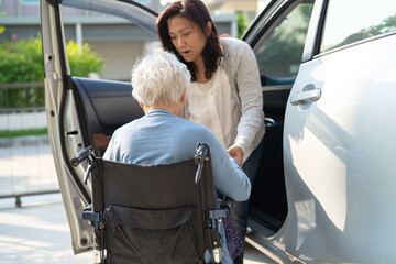 Caregiver help and support asian elderly woman sitting on wheelchair prepare get to her car to travel in holiday.