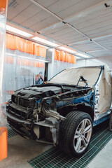 The body of the car and its elements are prepared for painting in the paint box. Automotive repair shop. Individual parts are covered with protective paper. Restoration of a car after an accident or