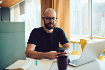 Fototapeta premium Happy man with laptop investing in successful startup on smartphone