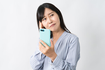 Fototapeta premium スマートフォンを持ちながら頭を抱える若い女性