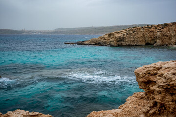 View from around Comino island, Malta. Scenery rocks in the sea. Moody spring time weather, cloudy day.