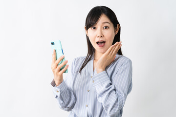 スマートフォンを持ちながらビックリをする若い女性