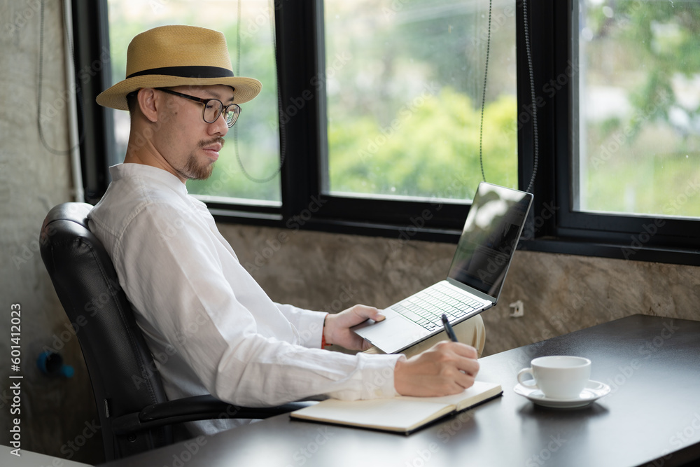 Aufkleber an asian businessman writing in a notebook for planning to work and using a laptop computer on a des