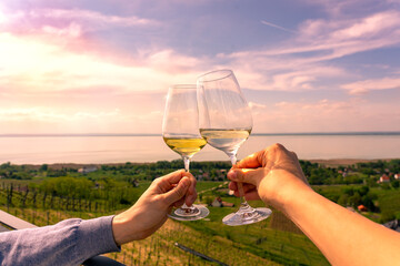 romantic celebratory toast with wine glasses in a Vineyard wine garden at Lake Balaton in Baracsony Hungray with beautiful view sunset