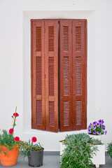 Wooden shutters and flower pots in front of an old traditional house in the city of Lindos on the...