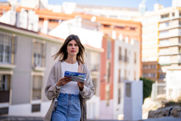 Young hipster woman on summer holidays holding map in city 