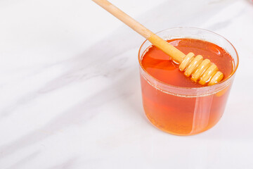 Honey dipper wooden honey stick in the jar macro close up shot on the light background