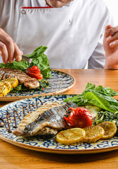 Chief cook preparing a plate of trout baked in butter