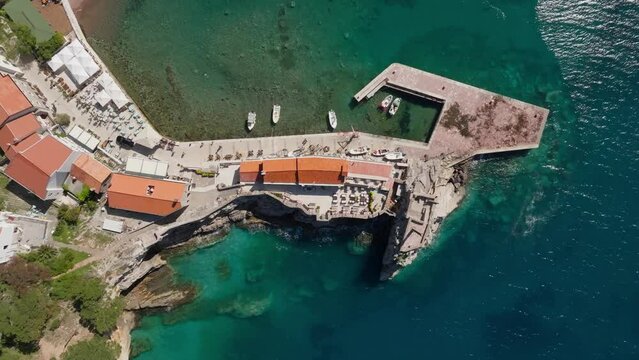Aerial view - Petrovac city in Montenegro, summer sunny day. top down drone shot. fishing boats in the harbour.