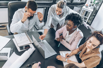 A diverse, casual design team collaborates in the office, creating innovative solutions and fostering in dynamic creative environment.