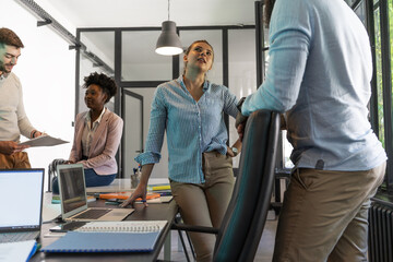 A diverse, casual design team collaborates in the office, creating innovative solutions and...